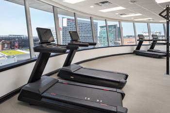 a row of treadmills in a gym with a view of the city at Vision On Lombard Baltimore, MD